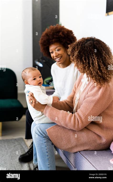Mother with son and aunt sitting on a sofa .